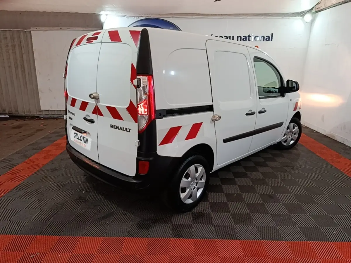 Renault Kangoo blanc vue 3/4 arrière droit avec bandes rouges réfléchissantes et porte latérale pleine.