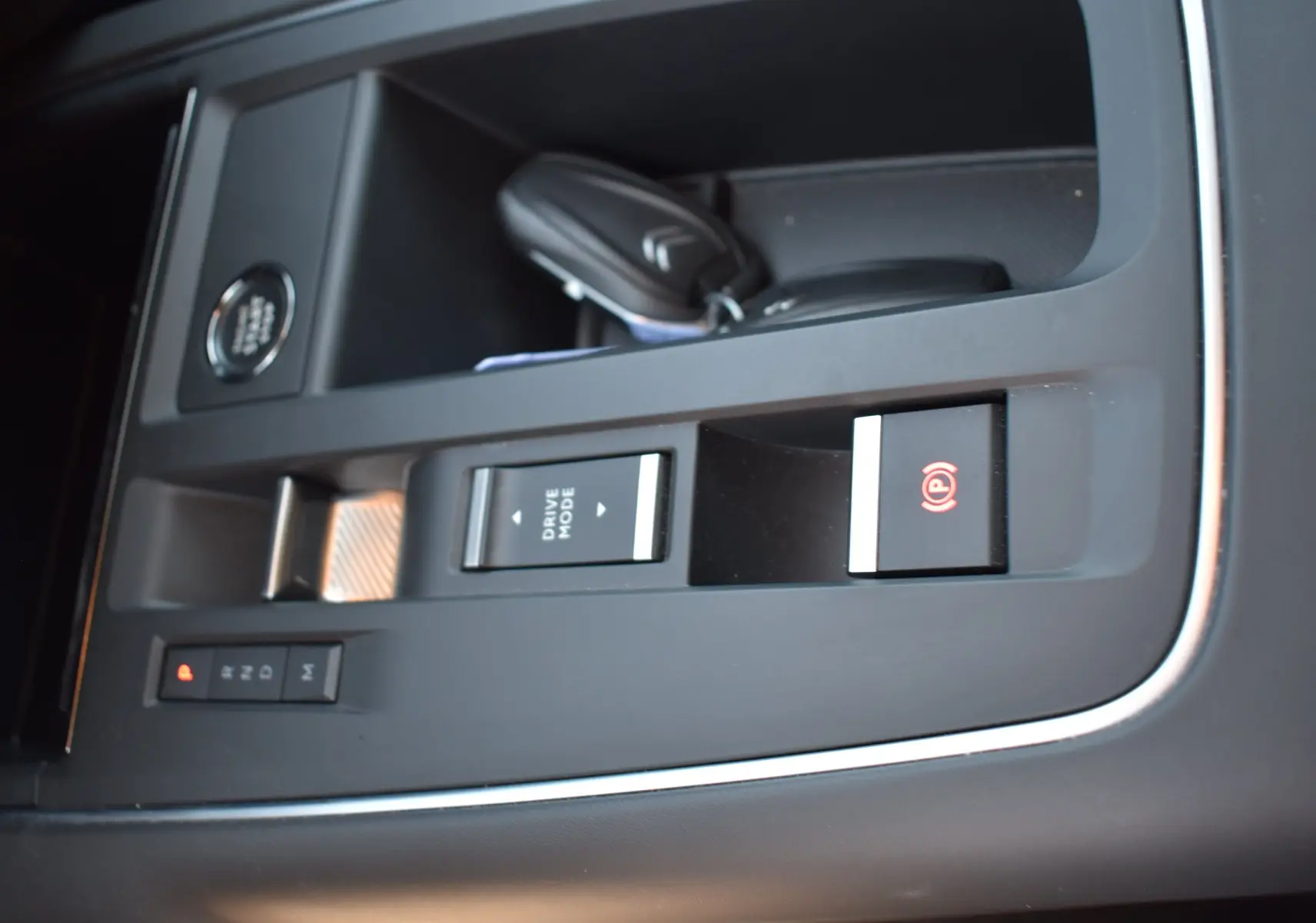 Gros plan sur la console centrale noire du Citroën C5 Aircross 2024 avec bouton Drive Mode et frein à main électronique.