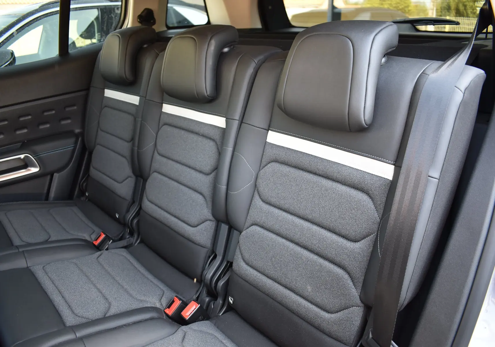 Vue intérieure sur la banquette arrière en tissu gris et cuir noir du Citroën C5 Aircross 2024, avec ceinture de sécurité visible.