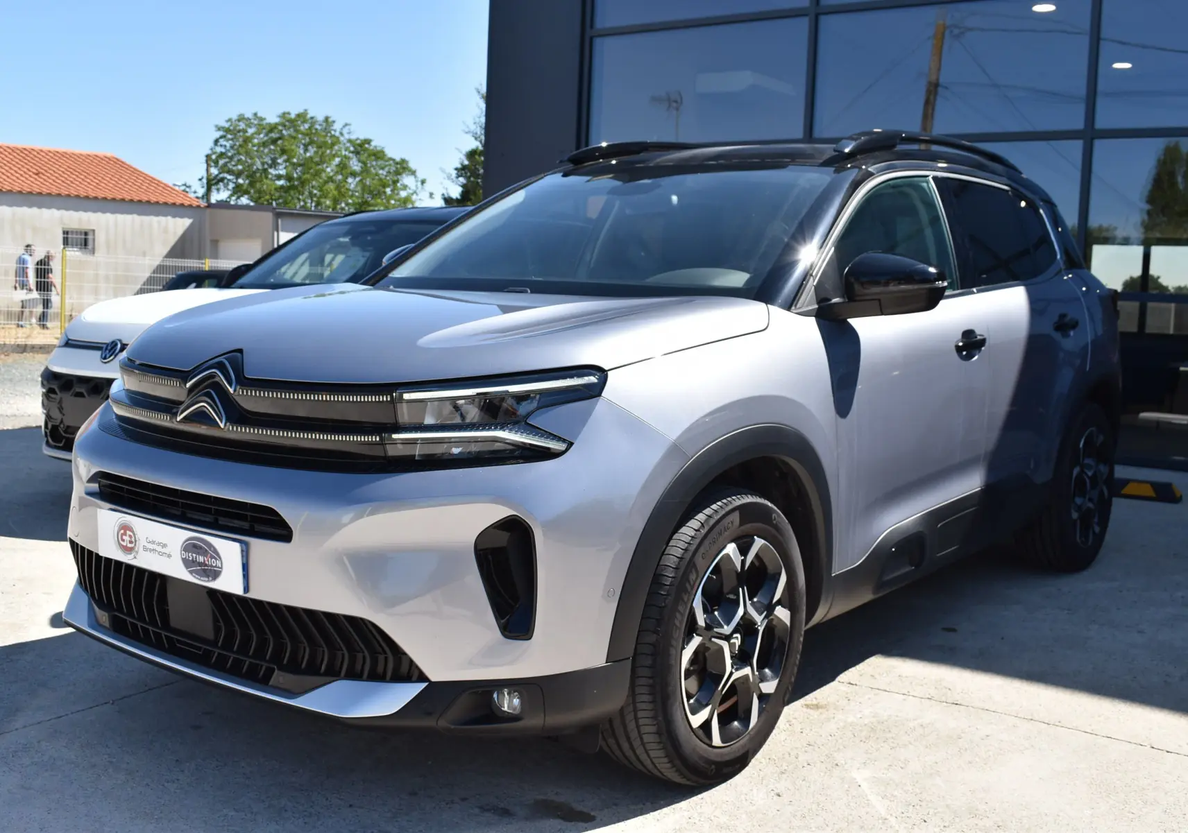 Citroën C5 Aircross 2024 gris métallisé vue 3/4 avant droit avec toit bi-ton noir et jantes distinctives.