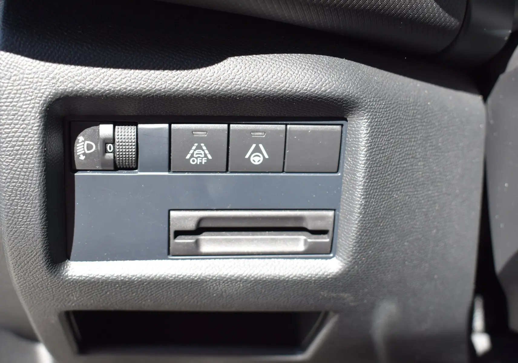 Gros plan sur les commandes de sécurité et réglage des phares du tableau de bord du Citroën C5 Aircross 2024.