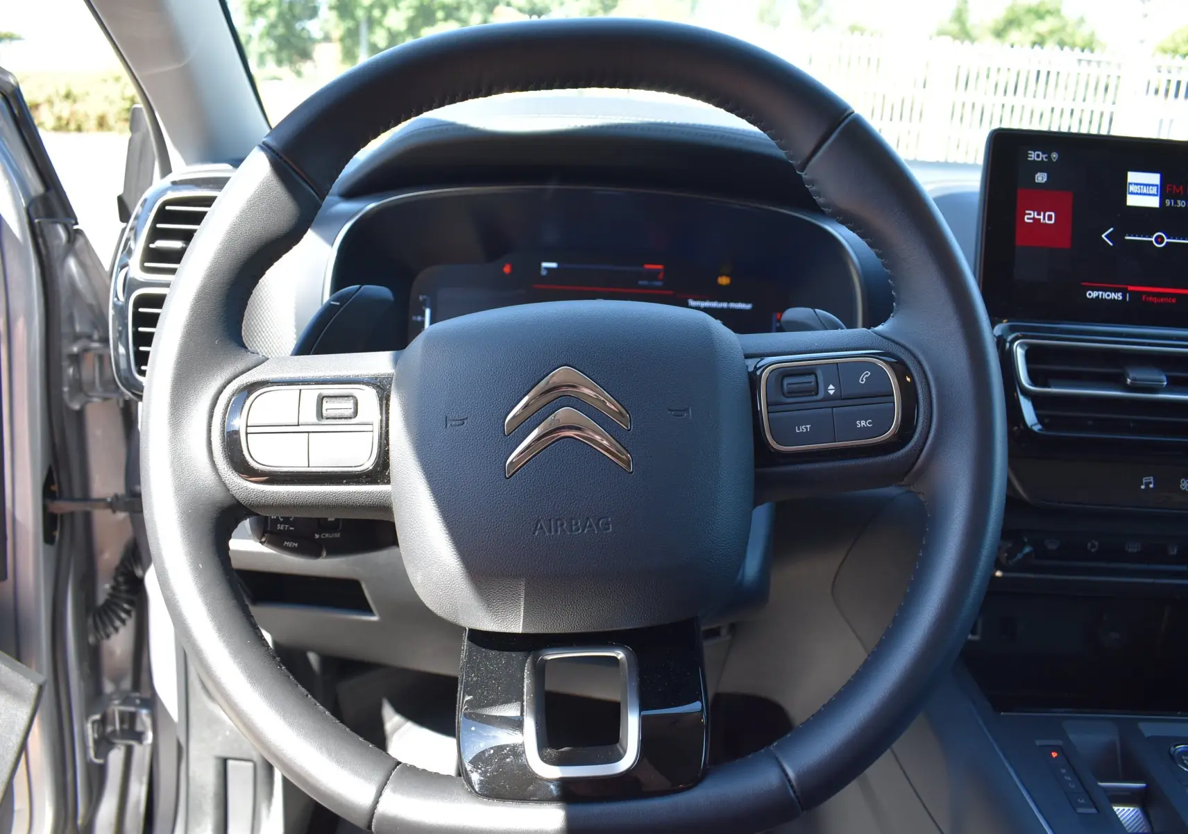 Vue rapprochée du volant noir du Citroën C5 Aircross 2024 avec tableau de bord digital et écran central tactile.
