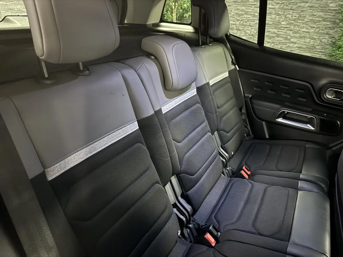 Vue intérieure des trois sièges arrière noirs et gris du Citroën C5 Aircross avec appuie-têtes et ceintures visibles côté droit.