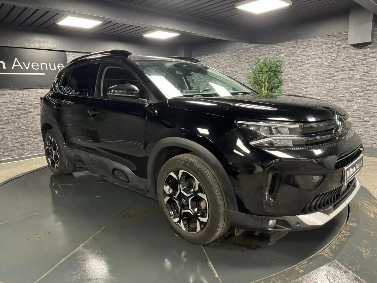 Citroën C5 Aircross noir perla Nera en 3/4 avant droit, avec jantes bi-ton et barres de toit noires brillantes.
