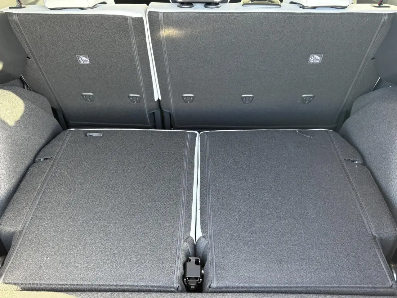 Vue rapprochée du coffre avec banquette arrière rabattue en tissu gris foncé du Citroën C3 Aircross Hybrid 2025.