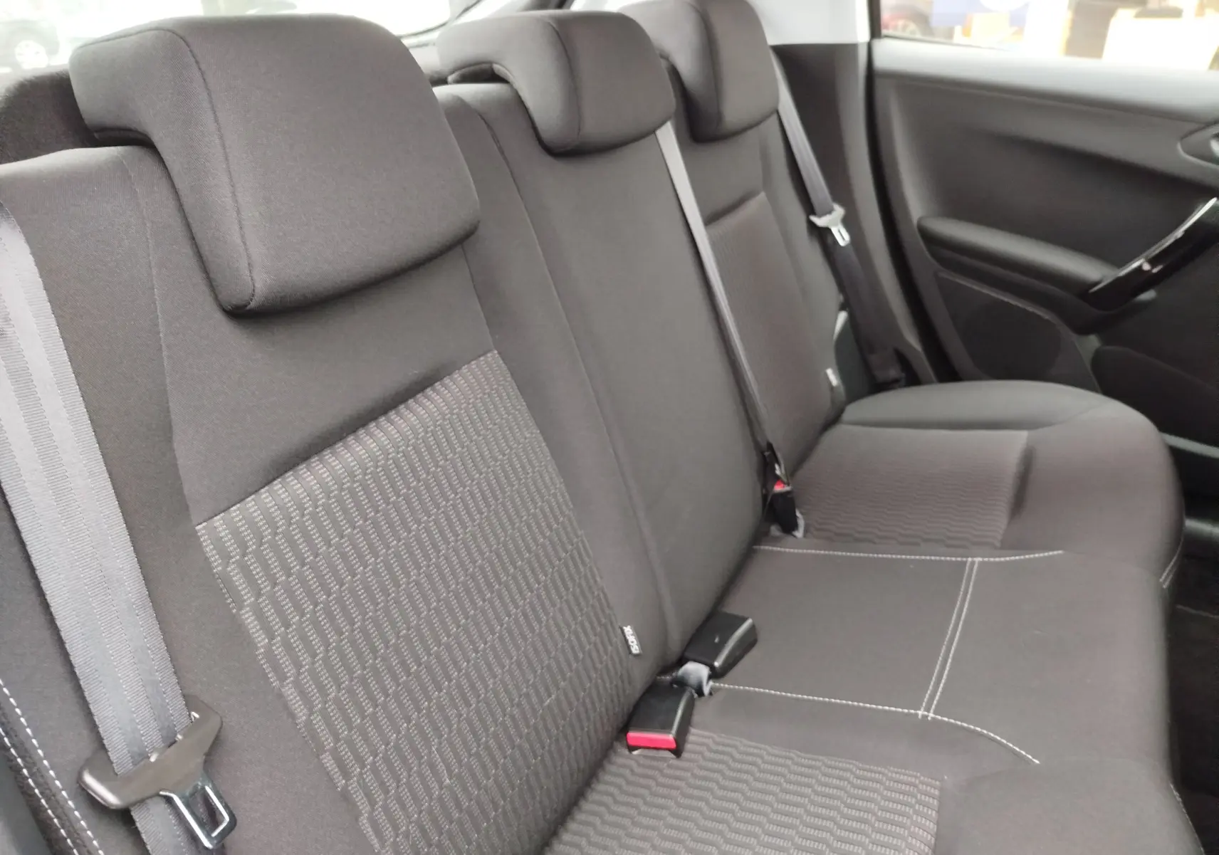 Vue intérieure côté droit des sièges arrière noirs de la Peugeot 208 2019 avec ceintures de sécurité visibles.