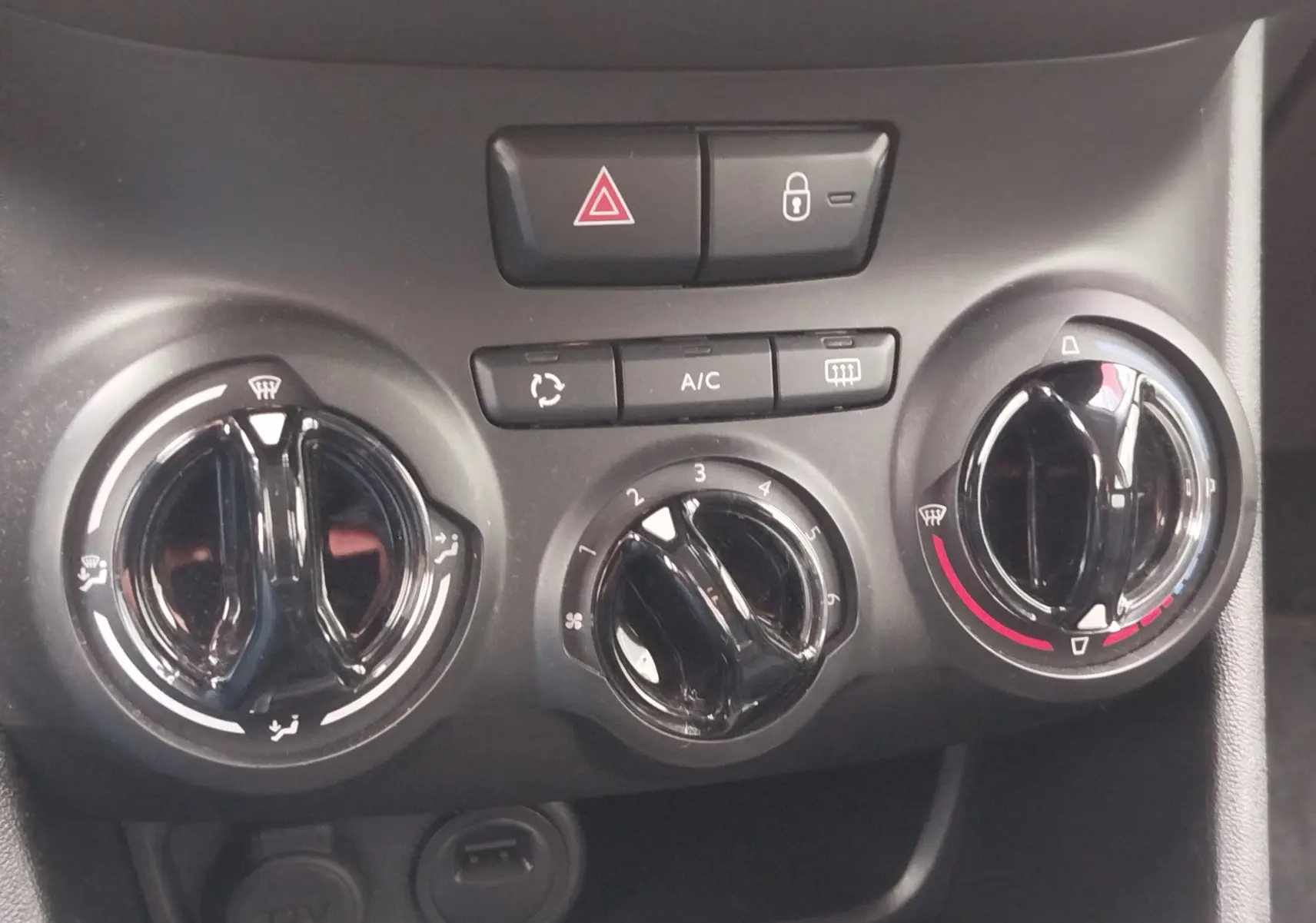 Détail des commandes de climatisation et sécurité du tableau de bord d'une Peugeot 208 noire, version diesel 2019.
