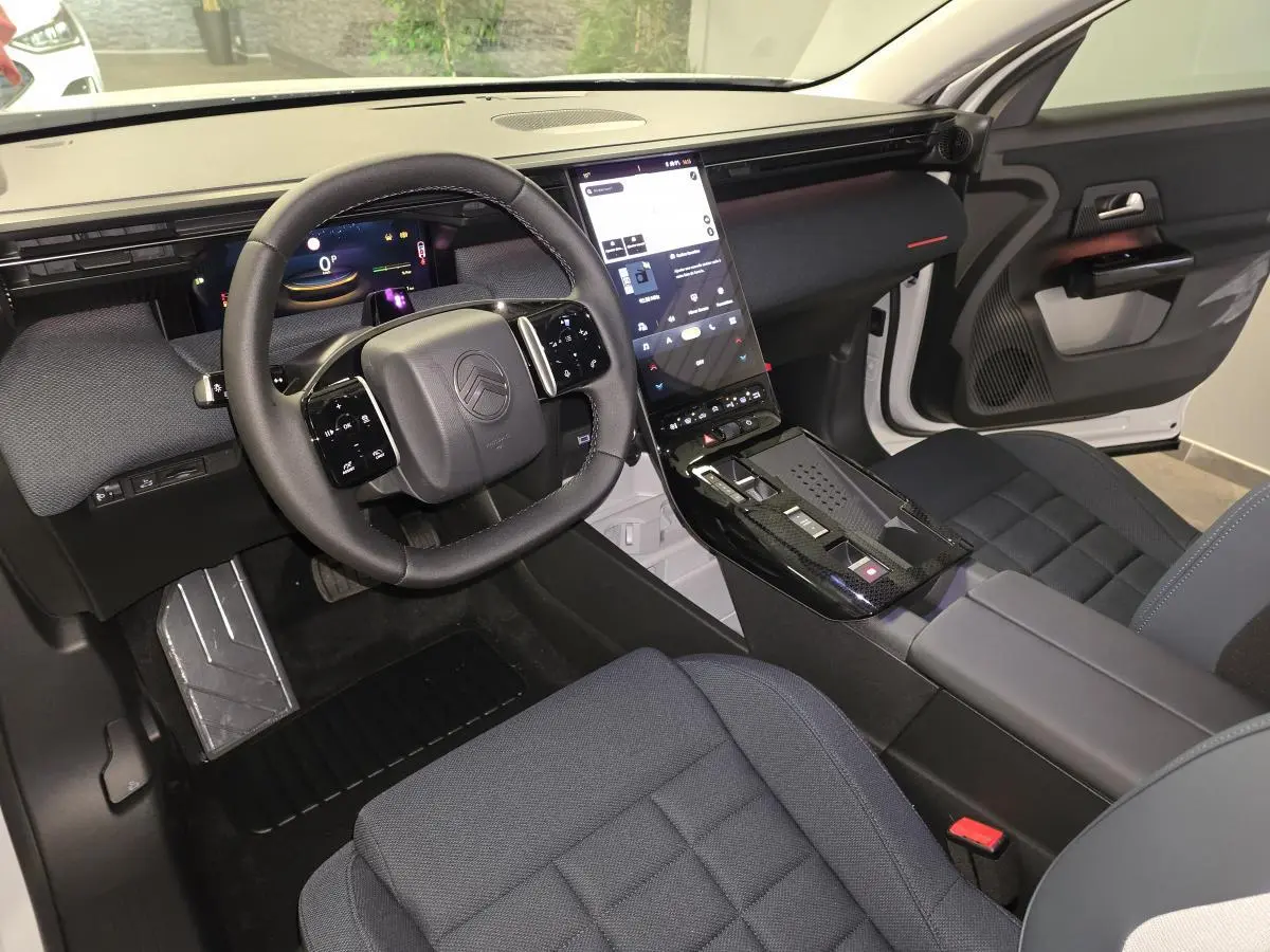 Vue intérieure avant droite du Citroën C5 Aircross 2026 avec tableau de bord numérique et sellerie tissu bleu.