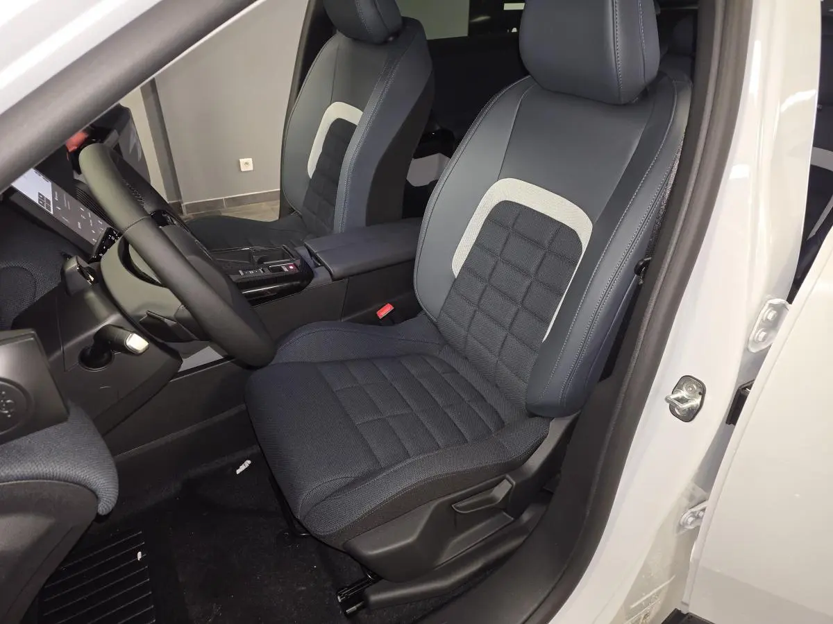 Vue intérieure côté conducteur du Citroën C5 Aircross blanc, siège tissu bleu avec insert clair et volant multifonctions.