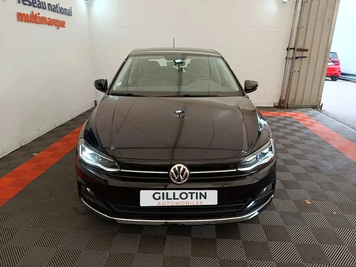 Vue avant d'une Volkswagen Polo noire 2020 avec phares LED allumés dans un garage intérieur.