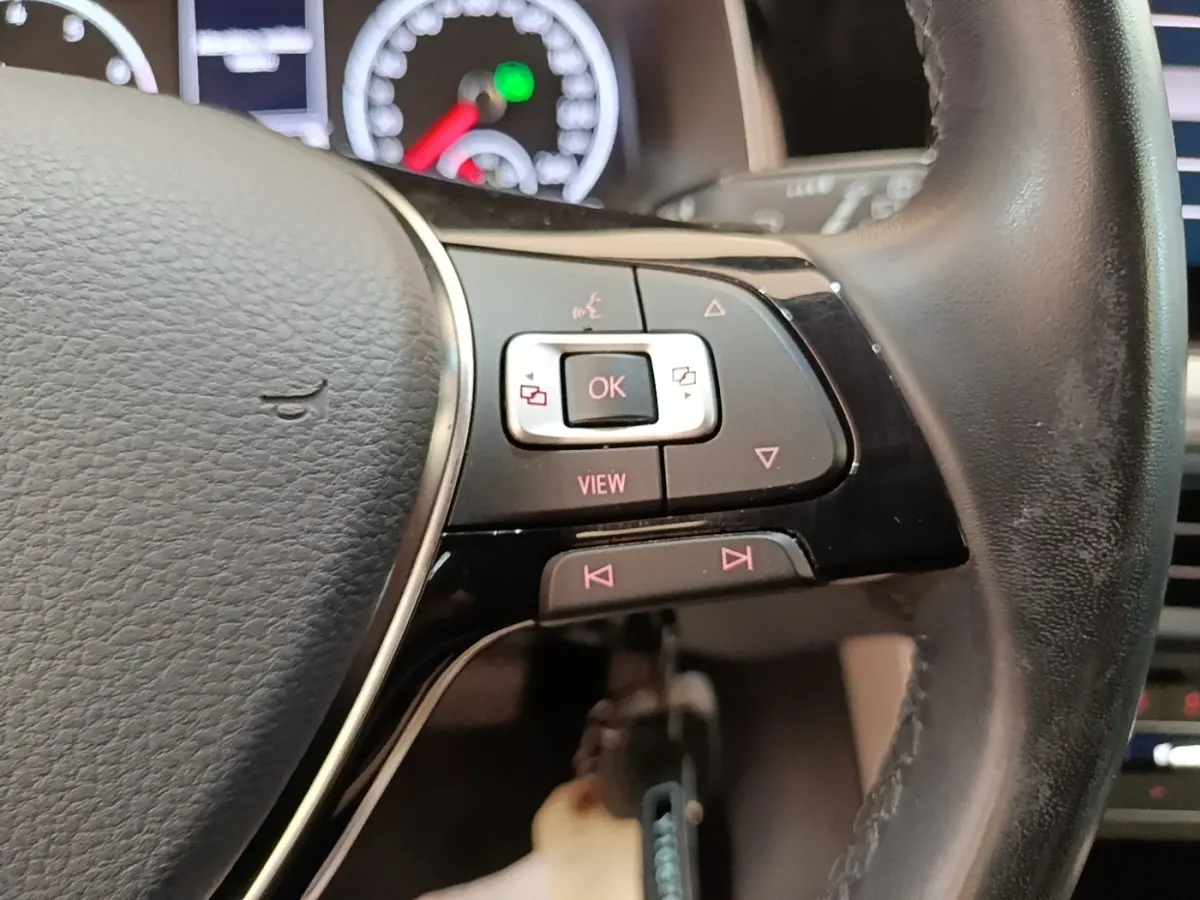 Gros plan sur le volant cuir noir de la Volkswagen Polo 2020, avec commandes multifonctions et tableau de bord en arrière-plan flou.