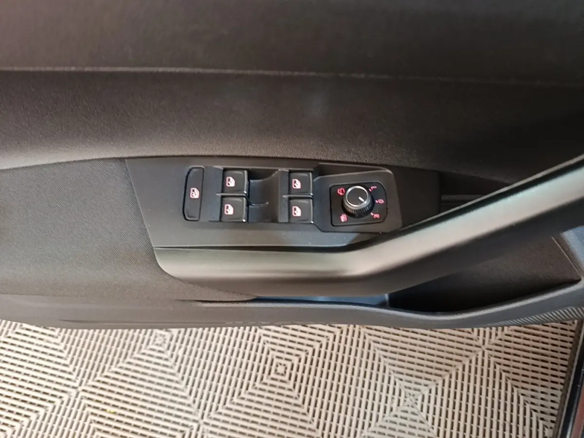 Vue rapprochée de la commande des vitres et rétroviseurs sur la porte côté conducteur d'une Volkswagen Polo noire.