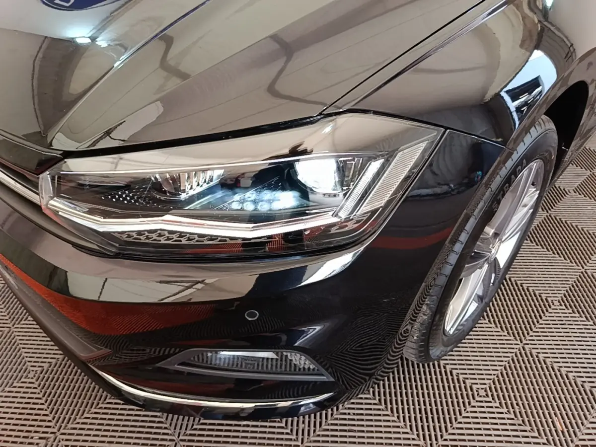 Gros plan sur le phare avant droit d'une Volkswagen Polo noire 2020 avec jante alliage et antibrouillard intégré.