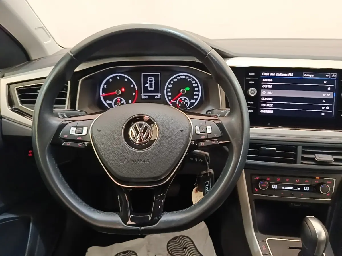Vue intérieure centrée sur le volant cuir noir et tableau de bord digital avec écran tactile de la Volkswagen Polo 2020.