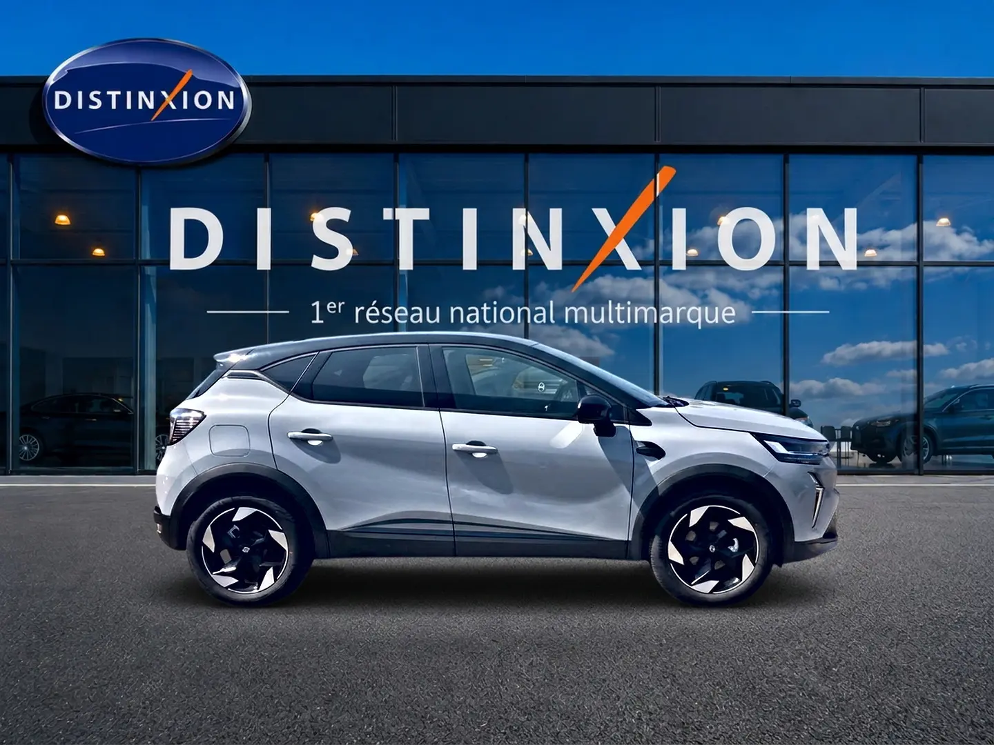 Profil droit du Renault Captur 2026 Rafale toit noir, avec jantes alu et becquet arrière visible devant une vitrine Distinxion.