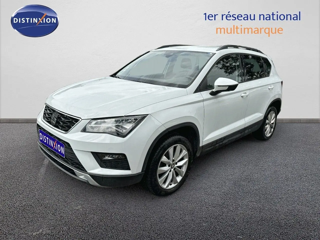 SEAT Ateca blanc en 3/4 avant droit, SUV compact avec jantes alliage et barres de toit noires visibles.