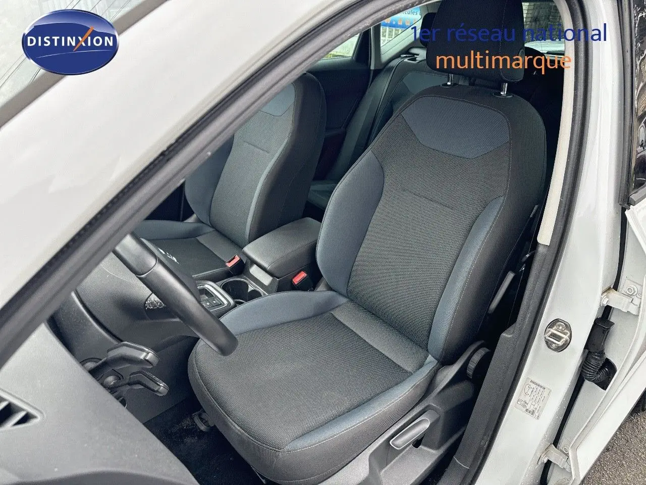 Vue intérieure côté conducteur du SEAT Ateca blanc 2018, montrant le siège avant en tissu gris et bleu.