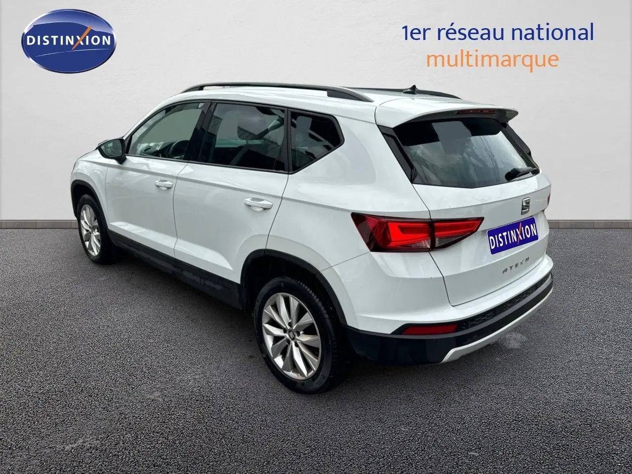 Vue 3/4 arrière droite d'un SUV SEAT Ateca blanc de 2018 avec jantes alliage et barres de toit noires.