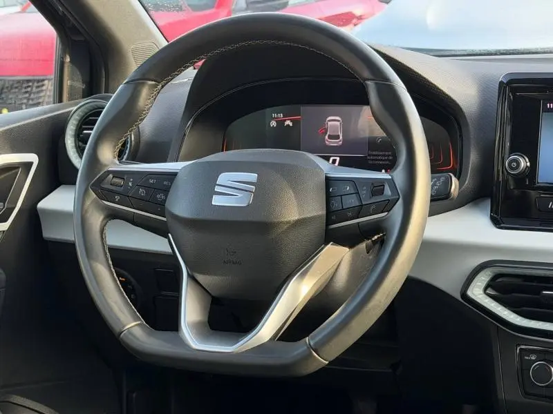 Vue rapprochée du volant multifonction de la SEAT Ibiza 2025, avec tableau de bord numérique et intérieur gris clair.