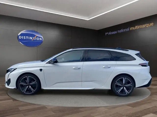 Peugeot 308 SW blanc nacré vue de profil côté gauche, break moderne avec jantes noires et toit vitré.