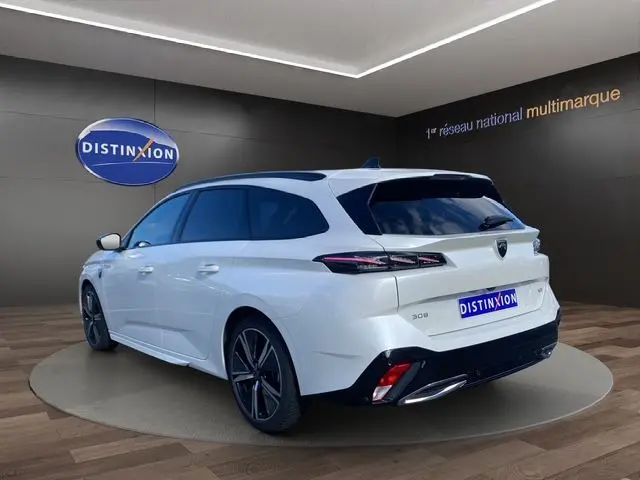 Peugeot 308 SW blanc nacré vue 3/4 arrière droit, break avec feux arrière LED et jantes alliage foncé.