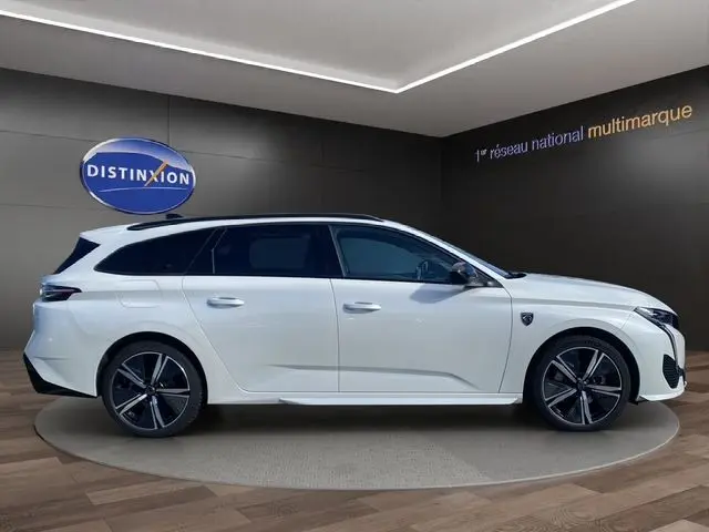 Peugeot 308 SW blanc nacré vue de profil côté gauche, break avec jantes alliage noires et toit noir contrasté.