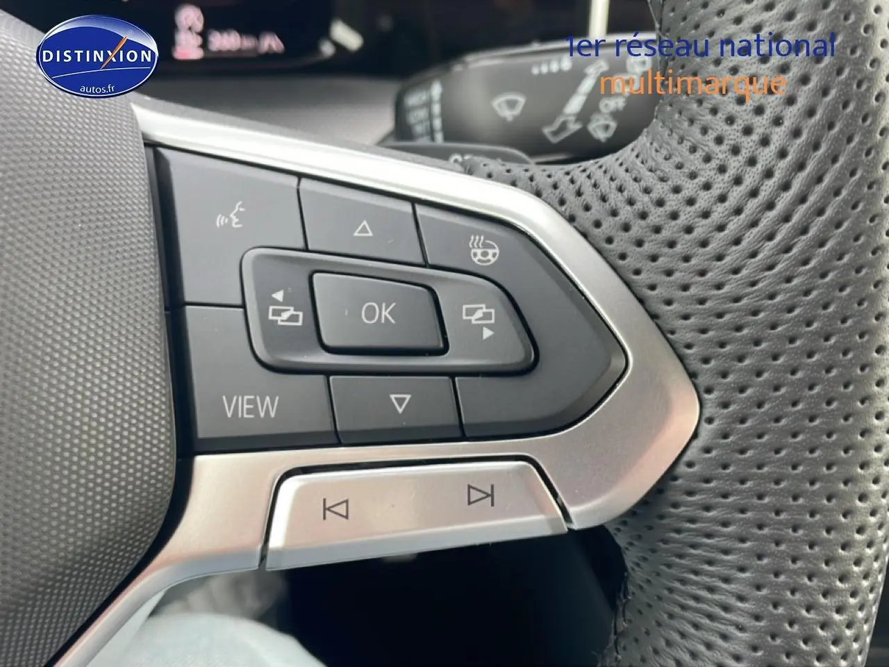 Gros plan sur les commandes multifonctions en cuir perforé du volant côté gauche de la Volkswagen Golf noire 2026.