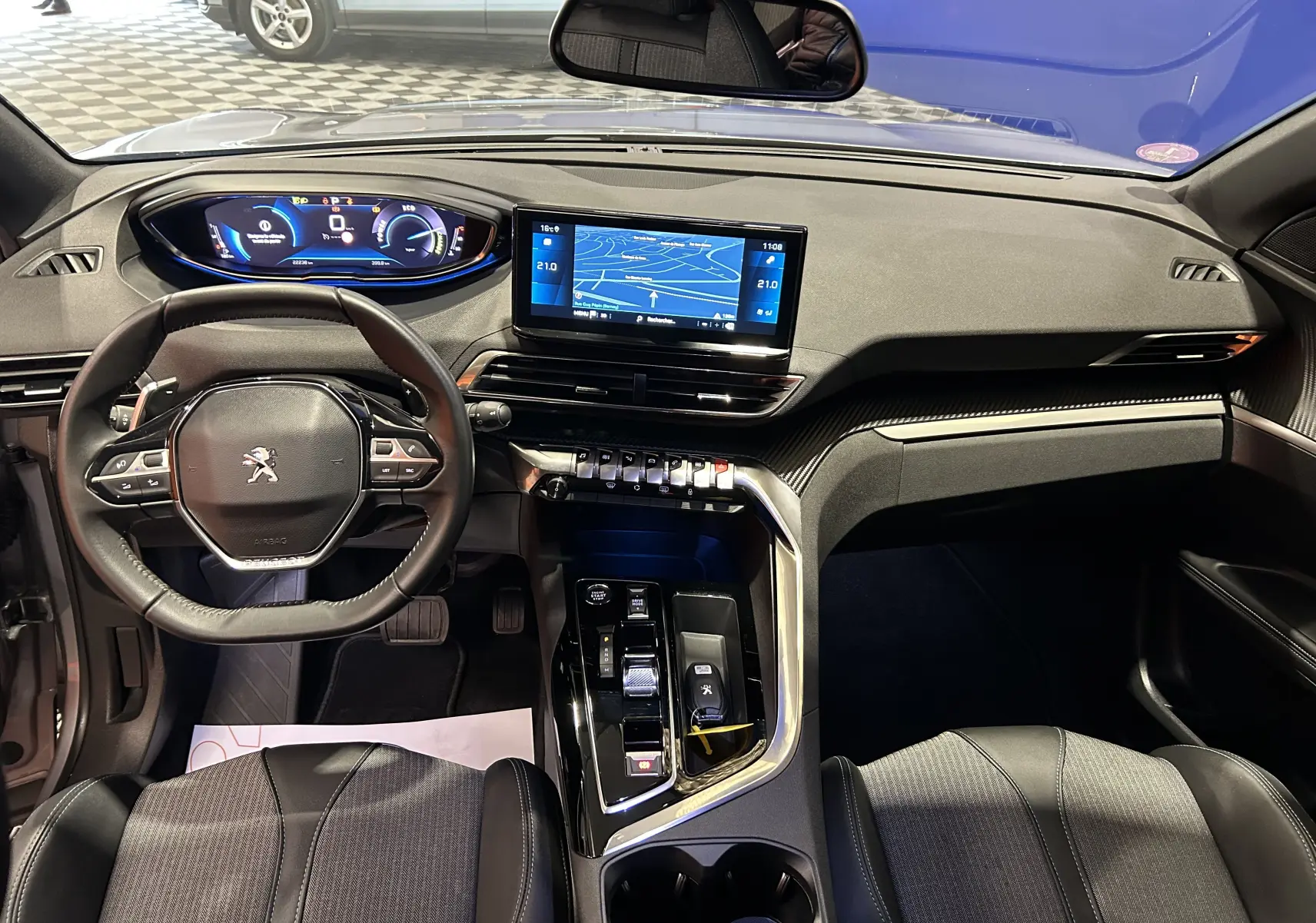 Vue intérieure avant du Peugeot 3008 Hybrid gris 2024, avec tableau de bord numérique et écran tactile GPS central.