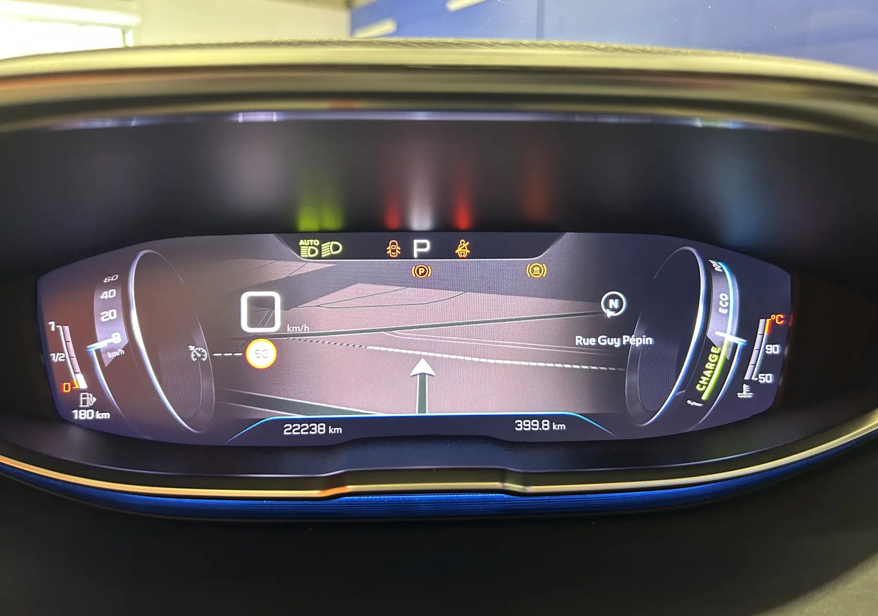 Tableau de bord numérique du Peugeot 3008 Hybrid gris, affichant la navigation et les indicateurs de vitesse et charge.