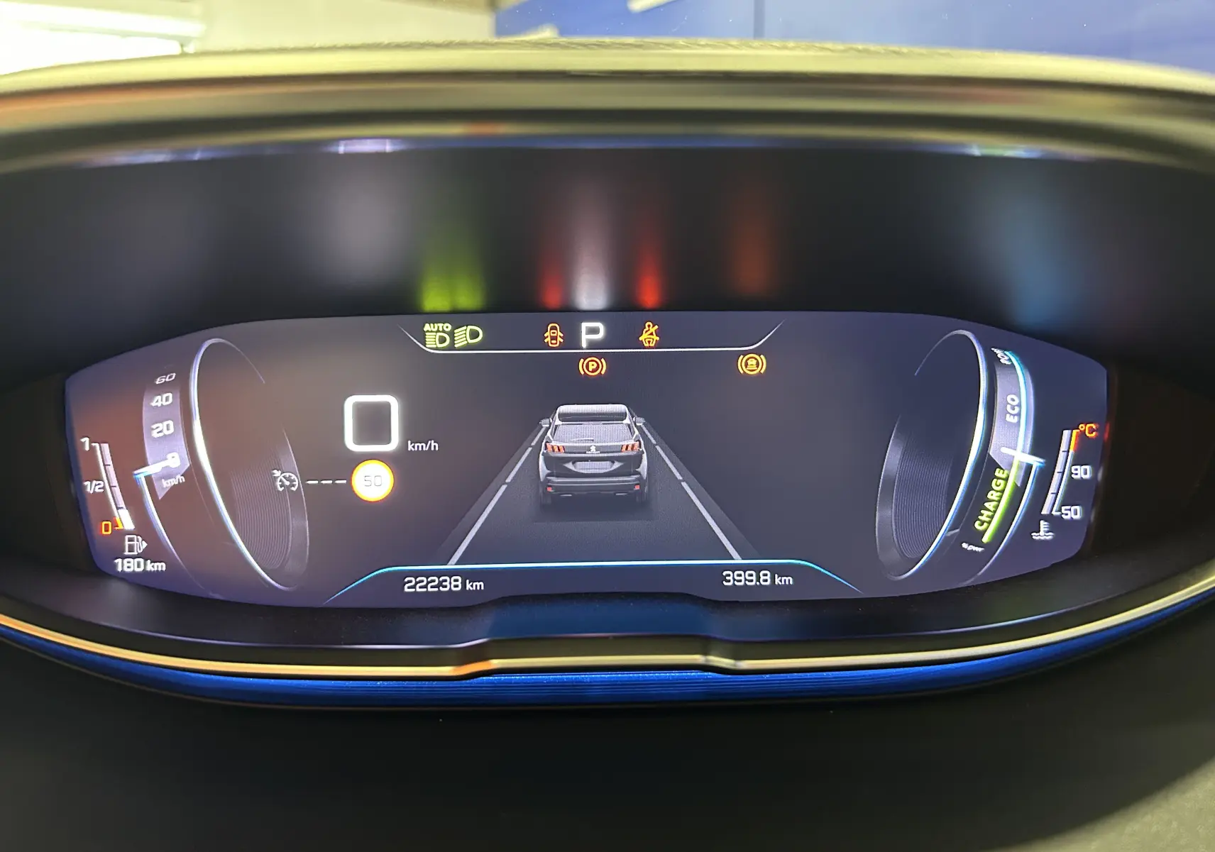 Tableau de bord numérique du Peugeot 3008 Hybrid gris, affichant la vitesse à 0 km/h et l'autonomie restante.