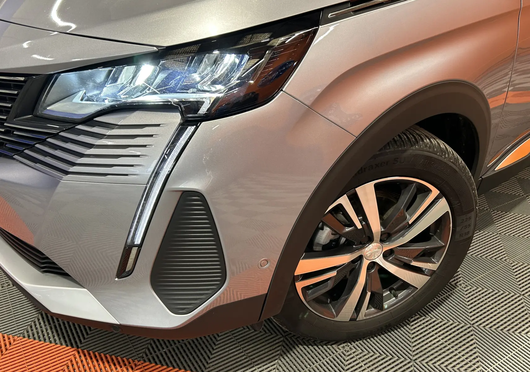 Gros plan sur l’avant droit gris du Peugeot 3008 Hybrid 2024, mettant en valeur le phare LED et la jante alliage.