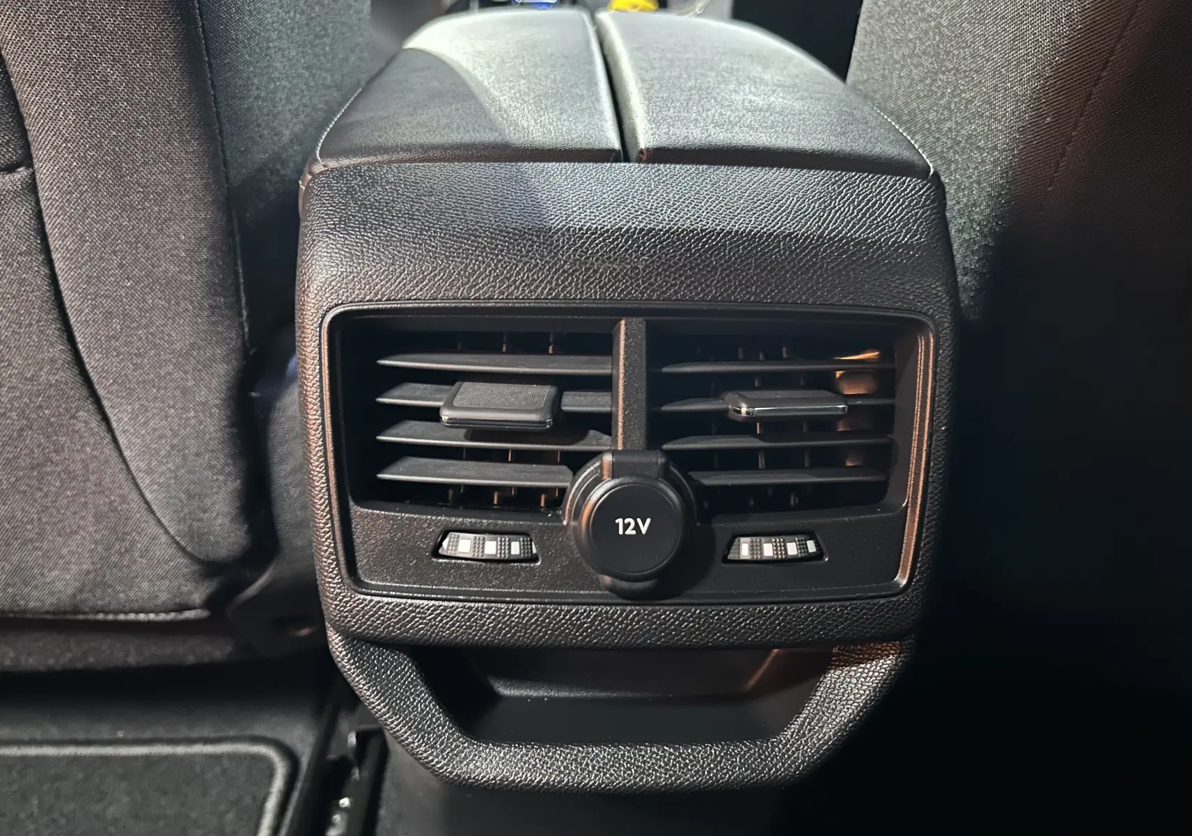 Détail des aérateurs arrière noirs avec prise 12V sur la console centrale d’un Peugeot 3008 gris.