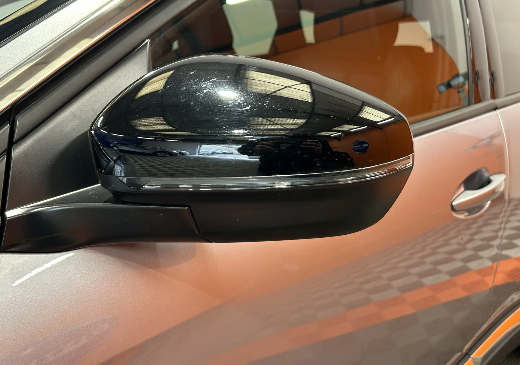 Gros plan sur le rétroviseur noir côté gauche du Peugeot 3008 gris, avec reflet de l'éclairage intérieur visible.