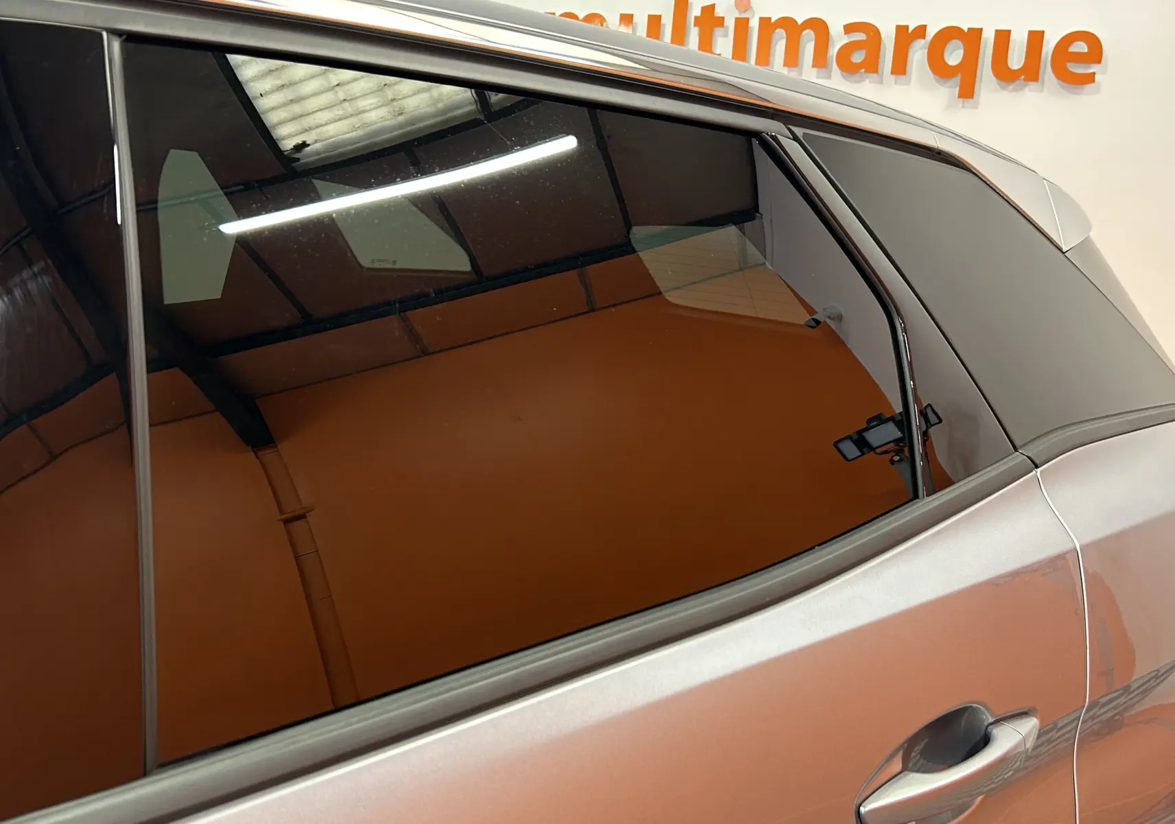 Détail sur la porte arrière côté droit d’un Peugeot 3008 gris 2024 avec vitre teintée et poignée intégrée.