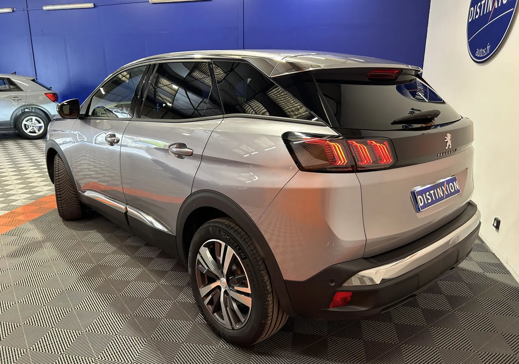 Vue 3/4 arrière droite d’un Peugeot 3008 gris hybride 2024 avec feux arrière LED et vitres teintées.
