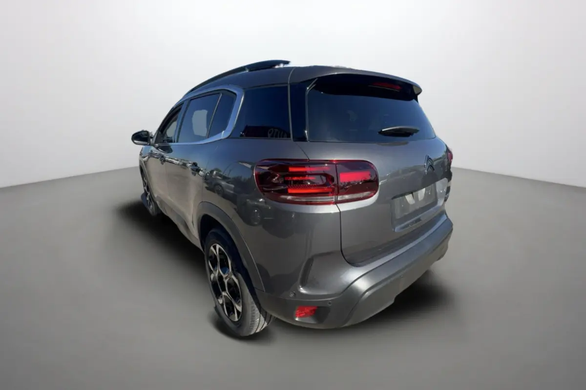 Vue 3/4 arrière droite d’un Citroën C5 Aircross gris platinium avec jantes alu 18 pouces et vitres surteintées.