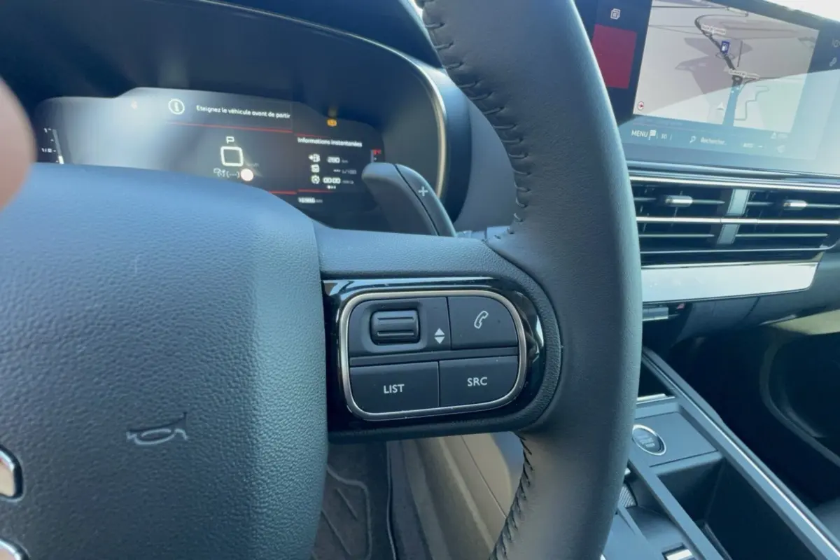 Gros plan sur le volant cuir multifonctions côté gauche du Citroën C5 Aircross 2025 avec écran tactile et tableau de bord numérique.