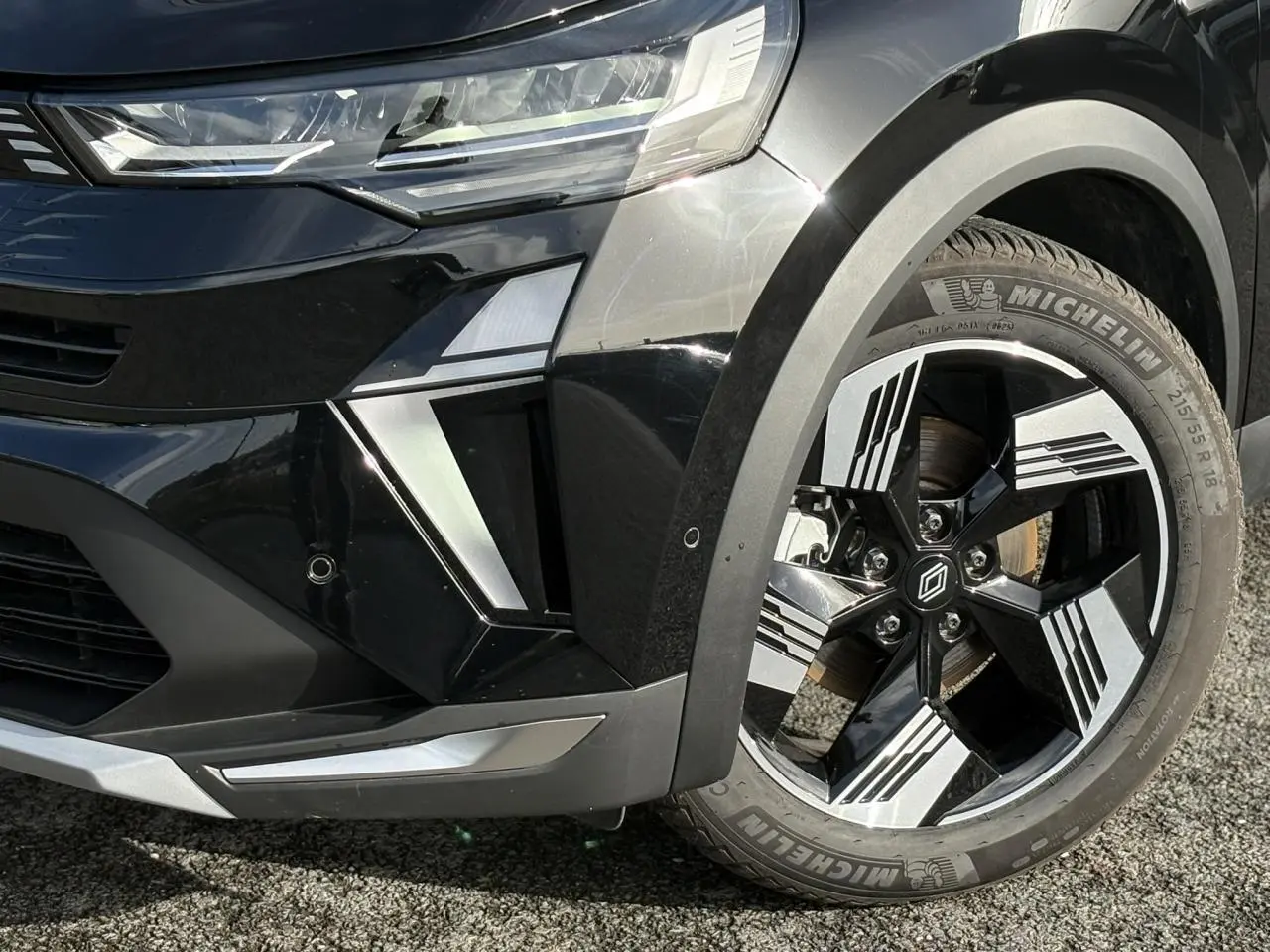 Gros plan sur l’avant droit noir étoilé du Renault Symbioz 2025, mettant en valeur la jante 18 pouces Gravity et le phare LED.