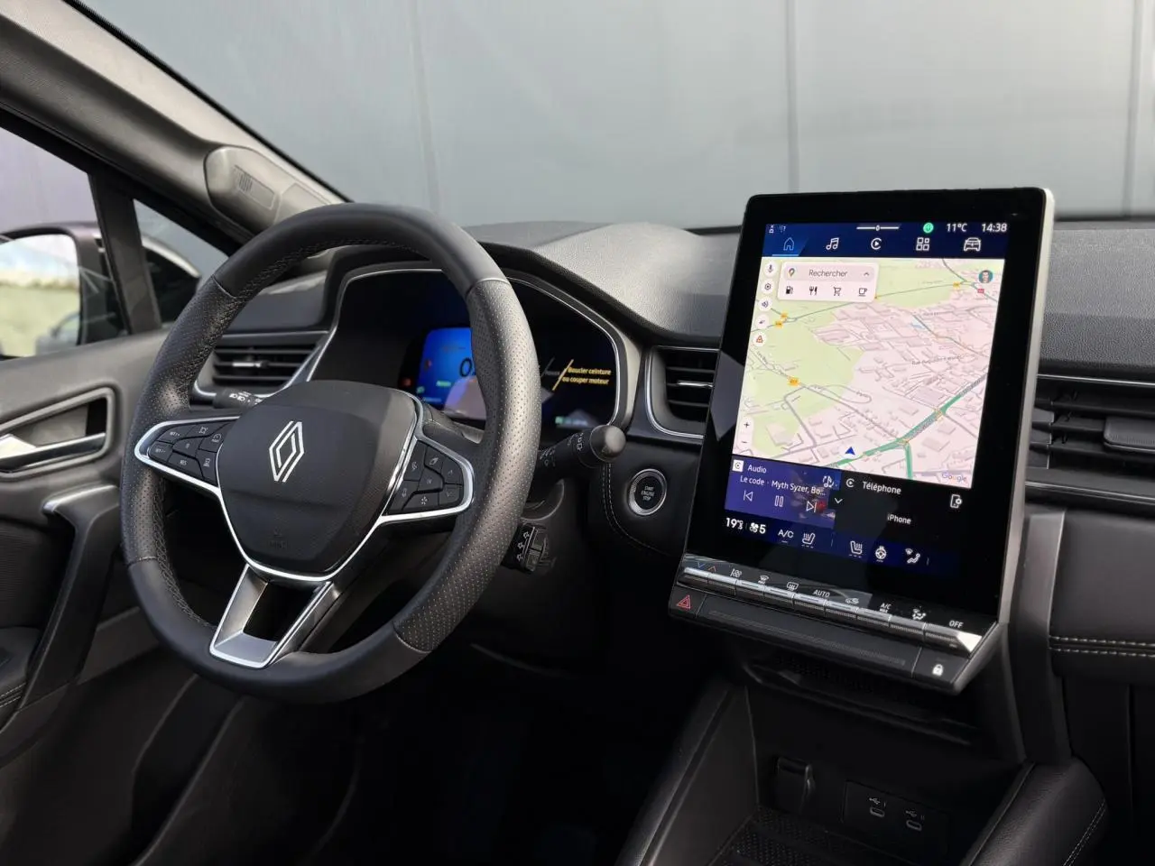 Vue intérieure côté conducteur du Renault Symbioz 2025, volant multifonction et écran tactile vertical avec navigation affichée.