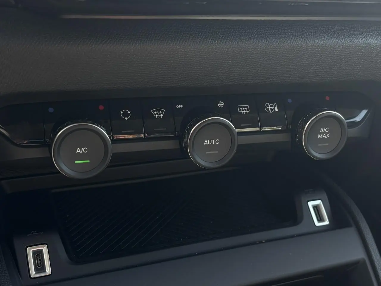 Gros plan sur la console centrale de la Citroën C4 Hybrid 145 e-DSC6 Max, boutons de climatisation et ports USB visibles.