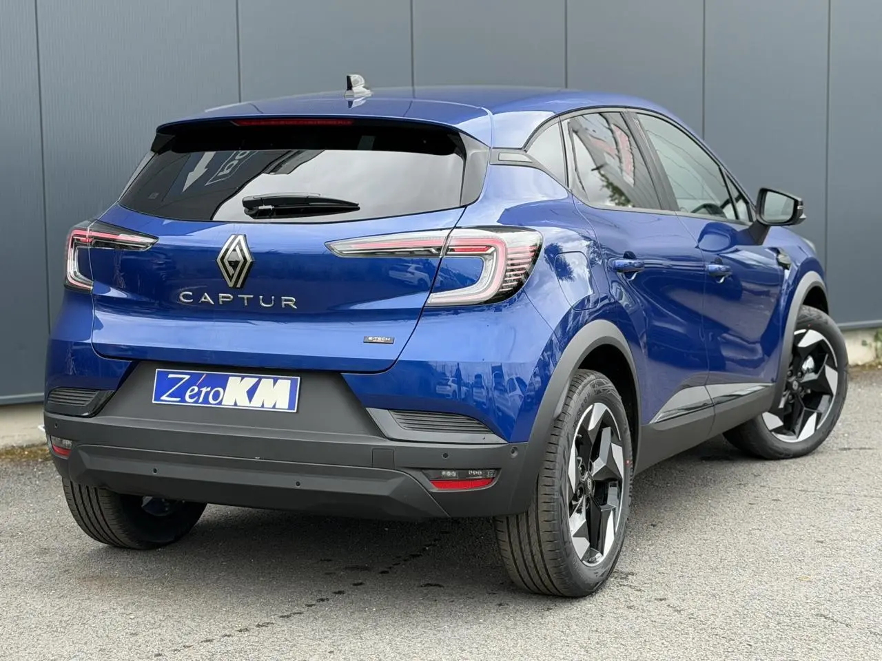 Vue 3/4 arrière droite du Renault Captur 2026 en Bleu Iron avec jantes aluminium noires et vitres surteintées.