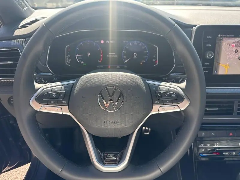Vue rapprochée du volant cuir multifonction du Volkswagen T-Cross 2026 avec tableau de bord numérique et écran tactile GPS.