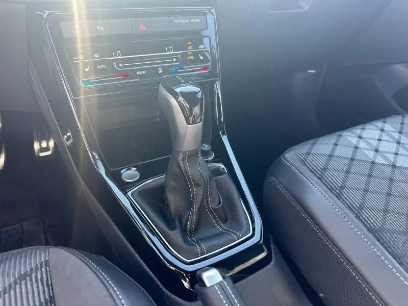 Gros plan sur la console centrale du Volkswagen T-Cross gris cendré, mettant en valeur le levier de vitesse automatique et les sièges en tissu R-Line.