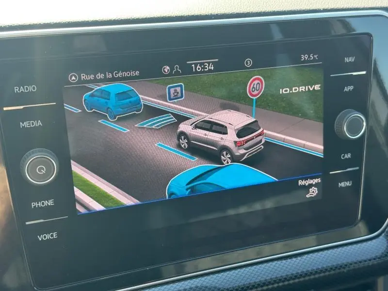 Écran tactile montrant une vue 3/4 arrière du Volkswagen T-Cross gris cendré avec signalisation routière virtuelle.