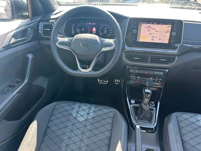Vue intérieure avant du Volkswagen T-Cross gris cendré, volant cuir multifonction et écran tactile GPS au centre.