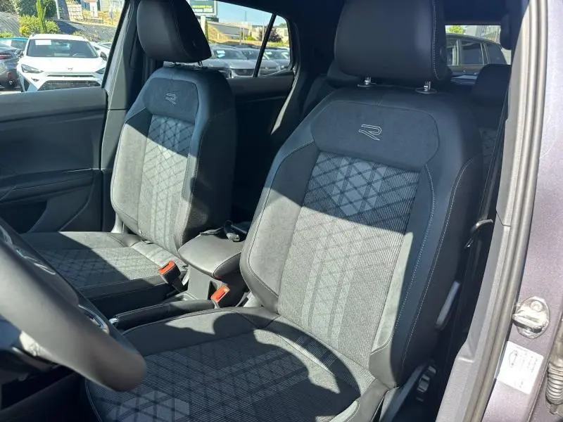 Vue intérieure des sièges avant R-Line en tissu gris/noir du Volkswagen T-Cross 1.0 TSI 116ch, avec accoudoir central et détails cousus.