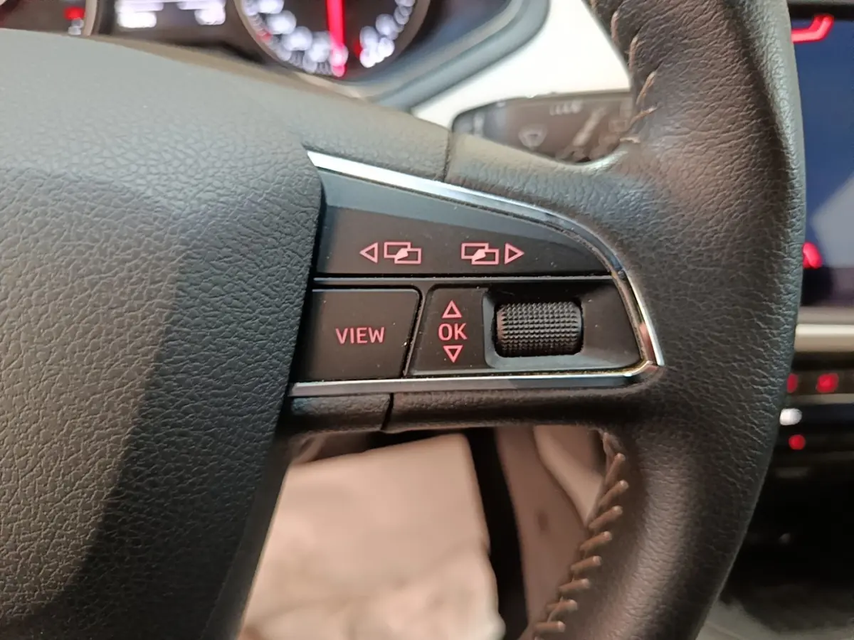 Gros plan sur les commandes à droite du volant cuir noir du SEAT Arona 2019, avec affichage digital en arrière-plan.