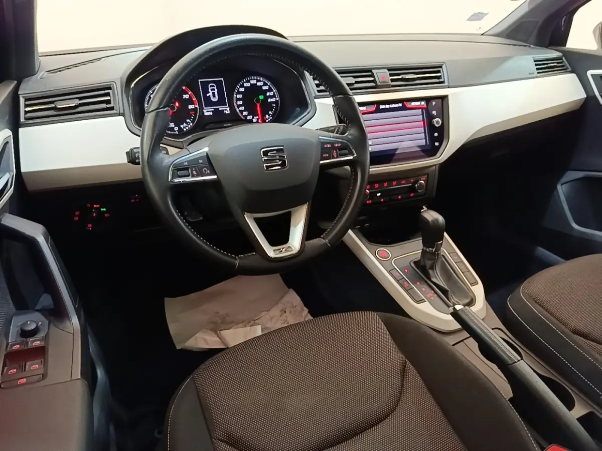 Intérieur du SEAT Arona 2019 vu côté conducteur, volant cuir, tableau de bord clair et écran tactile central.
