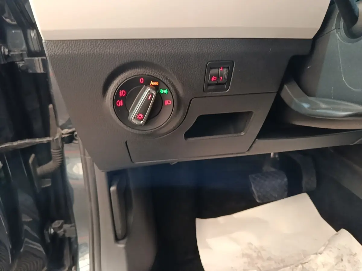 Gros plan sur la commande des phares à gauche du tableau de bord d’un SEAT Arona gris clair, intérieur noir.