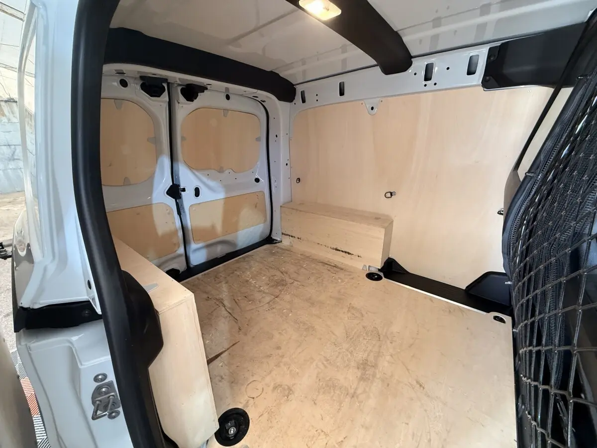 Vue intérieure arrière du Renault Kangoo blanc 2022, montrant l'espace de chargement avec parois et sol en bois.